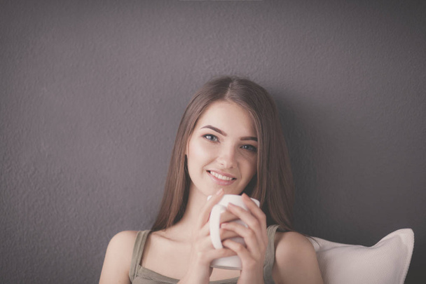 Beautiful woman with cup of aromatic coffee sitting on coach - Foto, Imagem