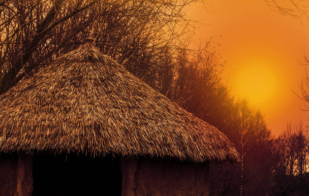 tető egy primitív otthon egy szalma tető naplementekor, természet táj, gyönyörű táj háttér - Fotó, kép