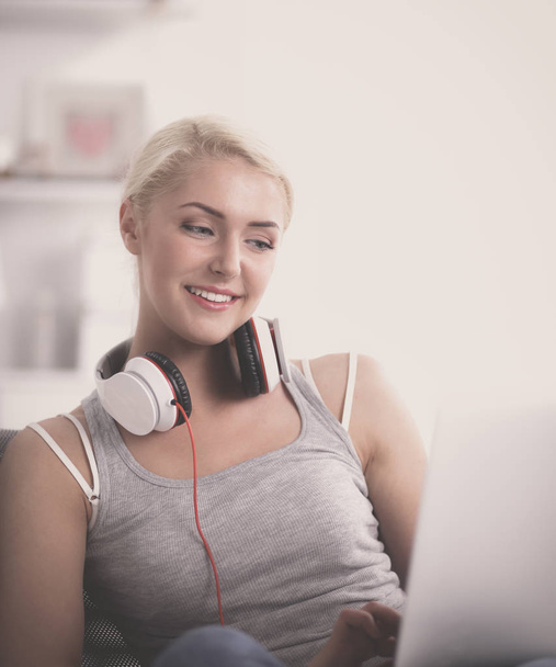 Young beautiful woman at home sitting on sofa and listening music - Photo, Image