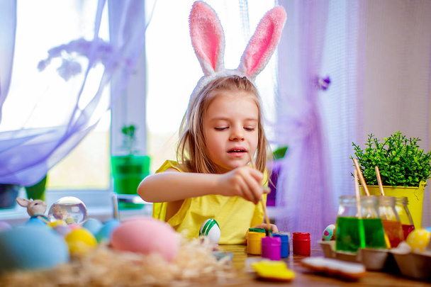 Happy easter girl in bunny ears painting eggs, small child at home. spring holiday - Foto, Bild