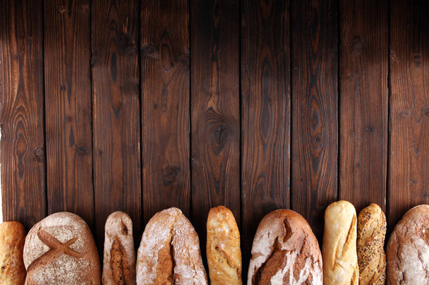 Assortimento di pane al forno e panini su fondo tavola in legno. Concetto poster della panetteria
 - Foto, immagini