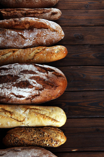 Pişmiş ekmek ve ekmek rulo ahşap masa arka plan üzerinde ürün yelpazesine. Fırın poster kavramı - Fotoğraf, Görsel