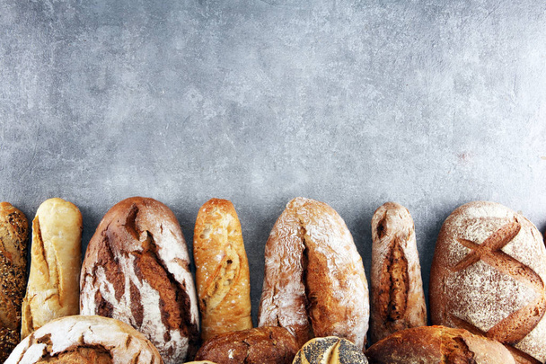 Sült kenyeret és zsemlét, a kő asztal háttér széles választékát. Pékség poszter koncepció - Fotó, kép