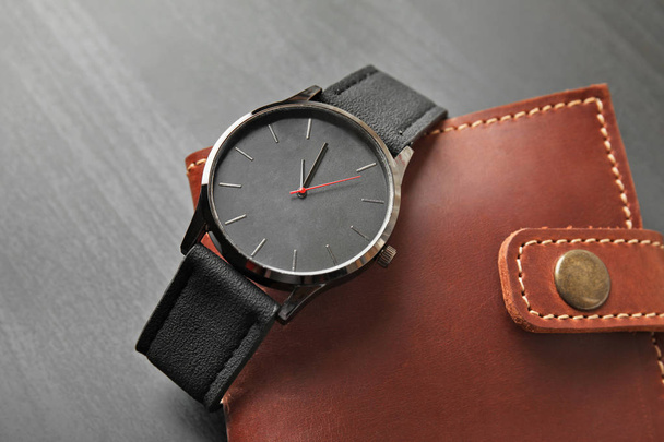 Stylish wrist watch and wallet on dark background. Fashion accessory - Foto, afbeelding