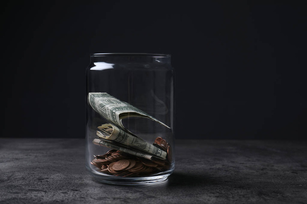 Donation jar with money on table against dark background. Space for text - Foto, imagen