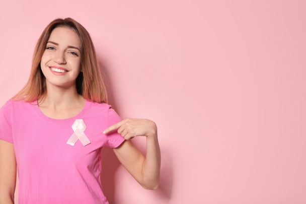 Woman with silk ribbon and space for text on color background. Breast cancer awareness concept - Photo, image