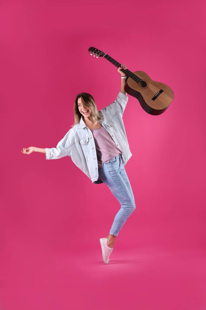 Young woman with acoustic guitar on color background - Fotó, kép