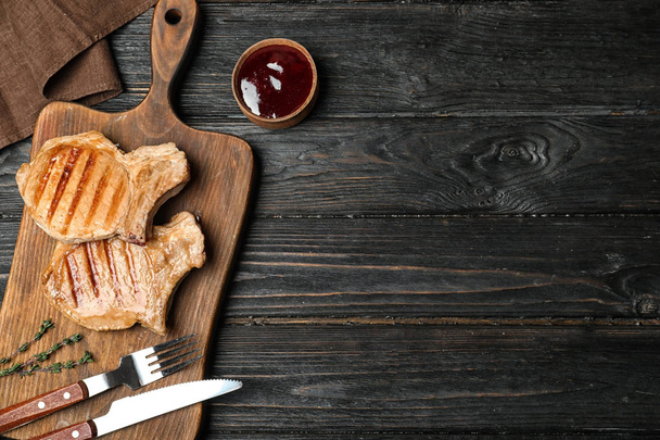 Grilled meat served with sauce on wooden background, flat lay. Space for text - Foto, Bild