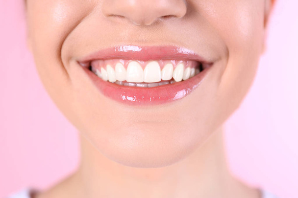 Young woman with healthy teeth and beautiful smile on color background, closeup - Zdjęcie, obraz