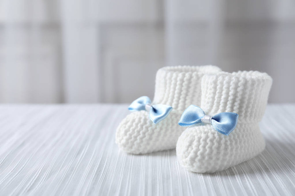 Handmade baby booties on plaid against blurred background. Space for text - Zdjęcie, obraz