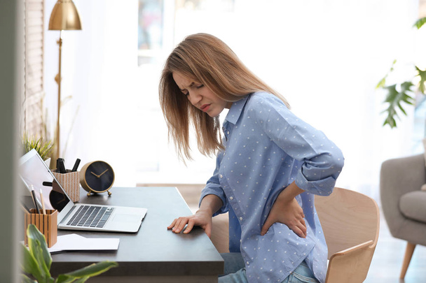Young woman suffering from back pain in office - Valokuva, kuva