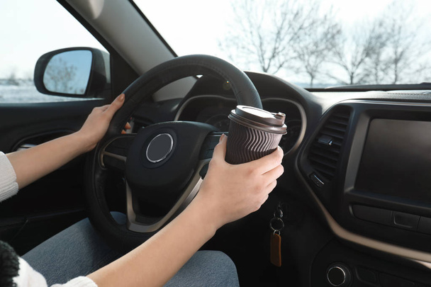 Young woman driving car and drinking coffee, closeup view. Cozy atmosphere - Photo, Image