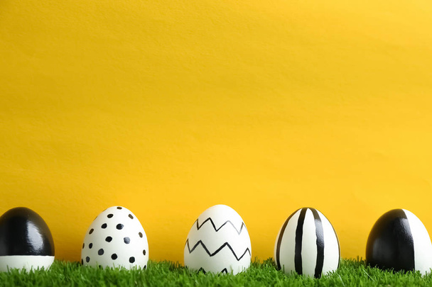 Line of painted Easter eggs on green lawn against color background, space for text - Φωτογραφία, εικόνα