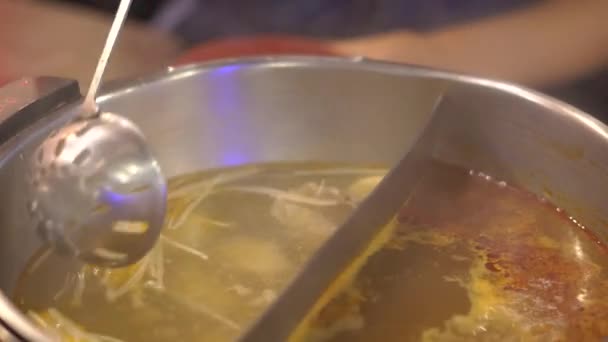 Young woman in an asian cafe cook food in a hot pot. Food is served on a conveyor on a little plates. Food conveyor. - Filmagem, Vídeo