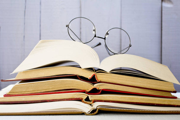 Open old books with glasses on wooden background. - Photo, Image