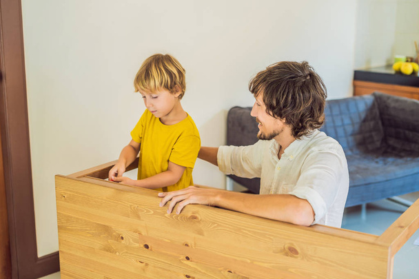 Father and son assembling furniture. Boy helping his dad at home. Happy Family concept - Valokuva, kuva