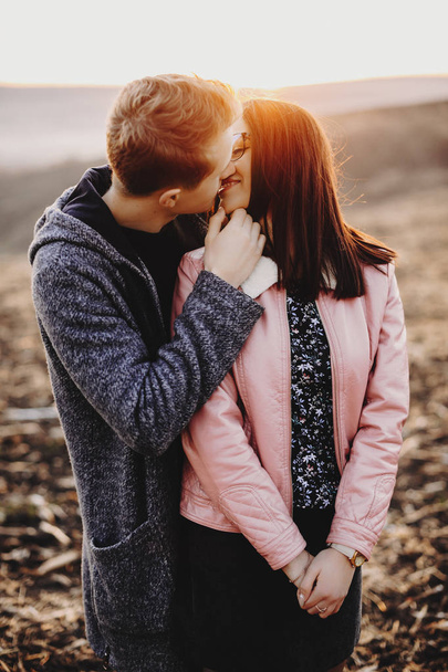 Εκπληκτικό πορτρέτο του όμορφη Καυκάσιος ζευγάρι φιλιά ενώ ο άνθρωπος αγγίζει το πρόσωπό της όμορφο ηλιοβασίλεμα φως ενώ ταξιδεύετε. - Φωτογραφία, εικόνα