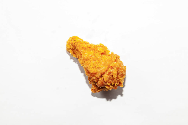 Detail jedné smažené mastné chutný jeden kuřecí křídla v hnědé mouky chov na bílém pozadí, nezdravých tukových potravin s zvýšený cholesterol způsobuje nemoc. - Fotografie, Obrázek