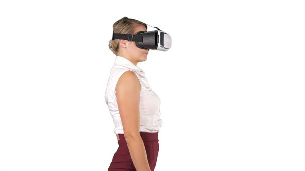 Woman in VR headset walking on white background. - Фото, изображение