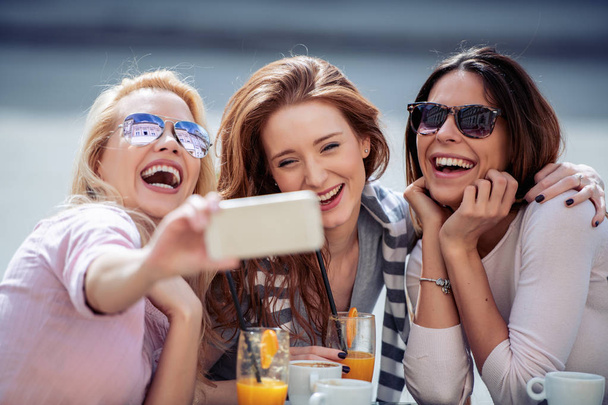 Holidays,people and fun concept-beautiful girls having fun in outdoor cafe. - Photo, image
