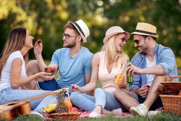 Happy friends in the park having picnic on a sunny day. - 写真・画像