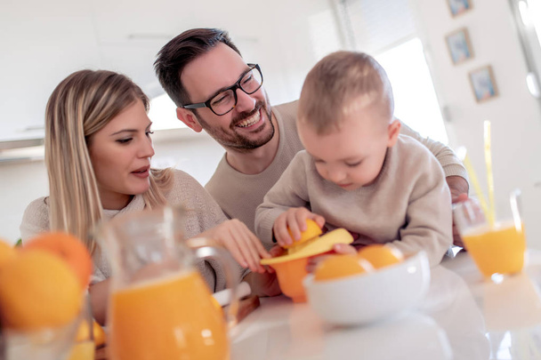 Family make fresh orange juice in their kitchen,having great time together.  - Photo, Image