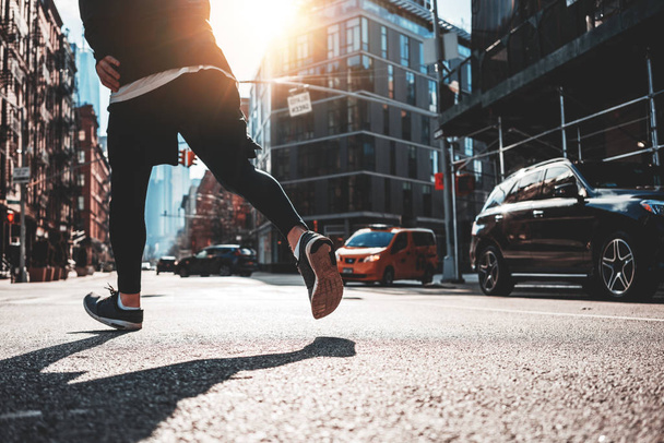 Close-up of athlete legs running through the New York streets. Sporty man fast running early morning in sunny day through urban city - Fotoğraf, Görsel