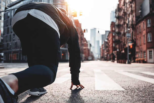 Sportowca w pozie start na ulicy miasta. Młody, sportowy prepearing uruchomić na miejskich przebiegających na ulicach Nowego Jorku - Zdjęcie, obraz