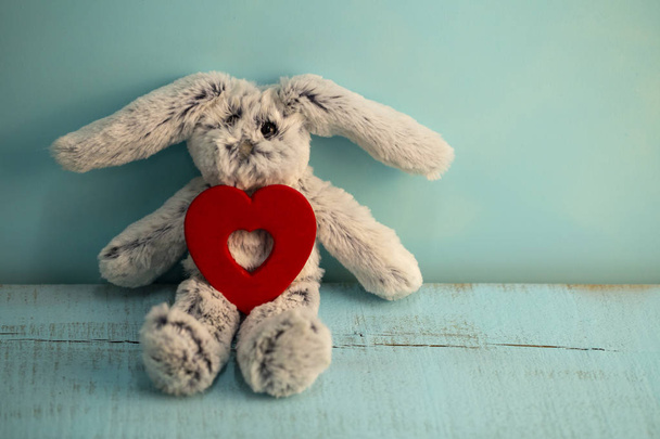 szary pluszowy królik z sercem na niebieskim tle drewnianych - Zdjęcie, obraz