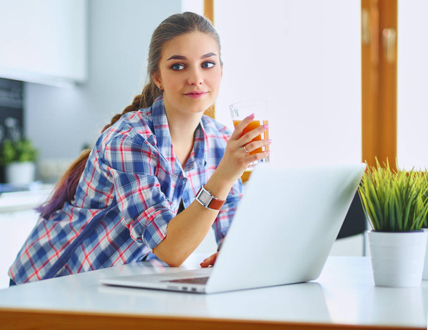 Young woman standing in kitchen using laptop - Photo, Image