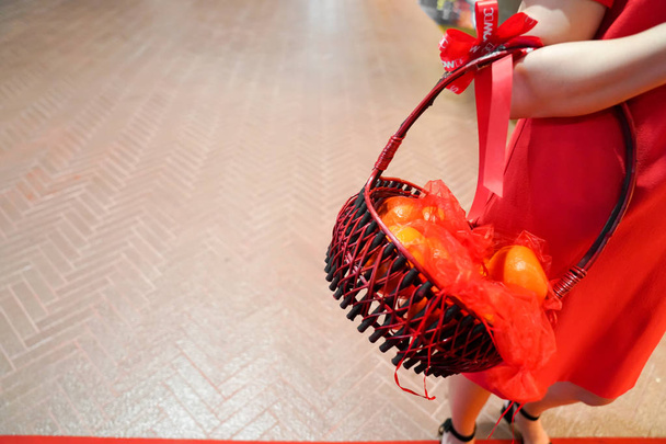 Chica en tela roja sosteniendo la naranja en la cesta, listo para el festival de año nuevo chino con primo mayor
. - Foto, imagen