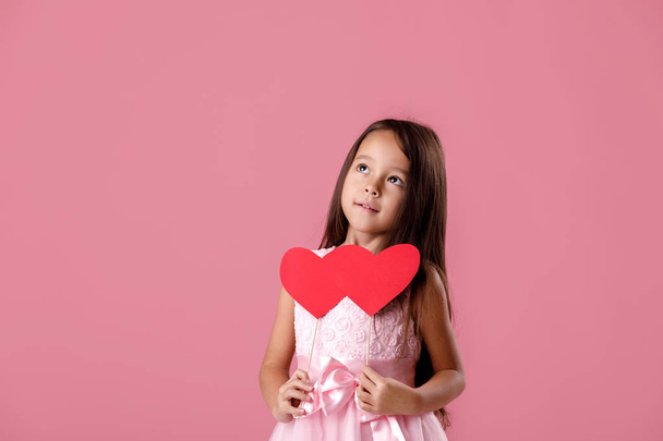 cute little girl in a pink dress holding a paper heart - 写真・画像