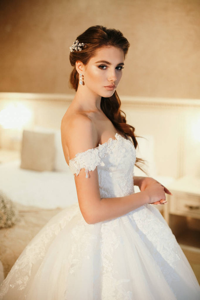 fashion  photo of beautiful  woman with dark hair in luxurious wedding dress posing in elegant interior - Fotoğraf, Görsel