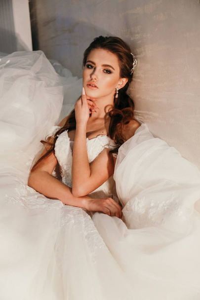 fashion  photo of beautiful  woman with dark hair in luxurious wedding dress posing in elegant interior - Foto, Imagen