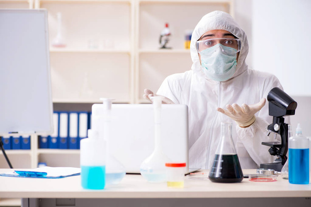 Молодой красивый химик, работающий в лаборатории  - Фото, изображение