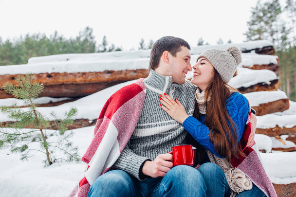 Young romantic couple with hot drink in winter forest. Couple in love - Foto, imagen