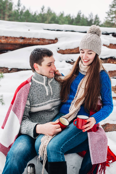 Young romantic couple with hot drink in winter forest. Couple in love - Φωτογραφία, εικόνα