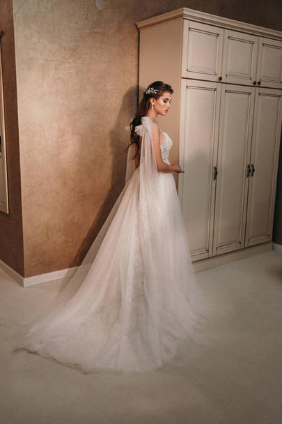 fashion  photo of beautiful  woman with dark hair in luxurious wedding dress posing in elegant interior - Фото, изображение
