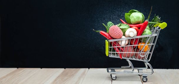 Shopping cart full, space for text, banner. Health bio organic food concept, cart in supermarket full of fruits and vegetables - Photo, image