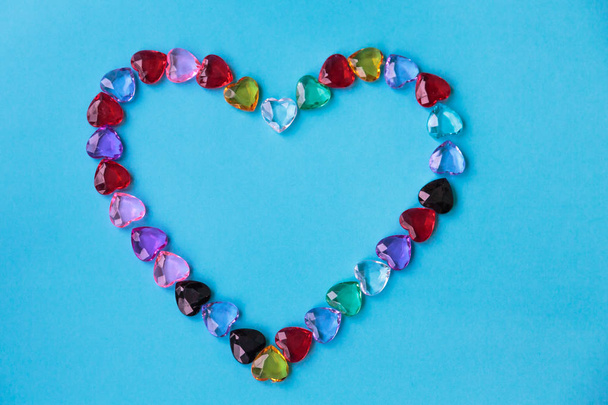 A big heart consisting of small multi-colored glass hearts on a blue background. - Photo, image