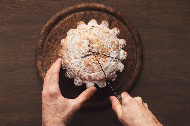 Hombre cortando pastel en mesa de cocina de madera
 - Foto, Imagen