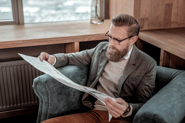 News review. Handsome man wearing glasses and sitting in hotel hall - Valokuva, kuva