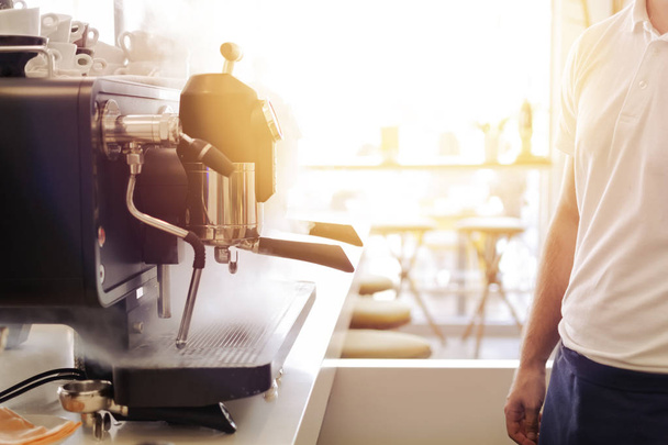 Barista standing infront espresso coffee machine in restaurant with warm sun glow - Φωτογραφία, εικόνα