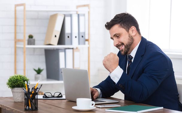 Щасливий бізнесмен з ноутбуком, святкуючи успіх в офісі
 - Фото, зображення