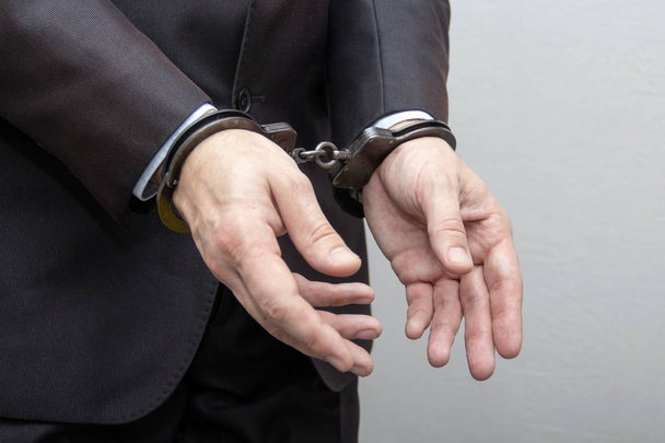 Человек в наручниках разговаривает по телефону, один звонок из тюрьмы, разговаривает с адвокатом, бизнесмен в полиции, правосудие
 - Фото, изображение