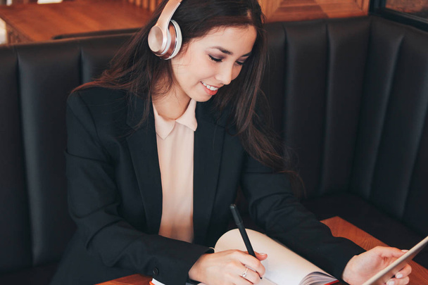 Krásná okouzlující brunetka usmívající se Asijská dívka v sluchátka s tabletem v kavárně, student, na volné noze. Studium cizích jazyků nebo online kurzy - Fotografie, Obrázek