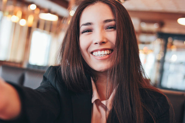 Belle brune souriante asiatique fille prenant selfie sur caméra frontale au café
 - Photo, image
