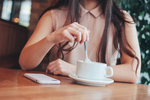 Crop photo of young woman girl with cup of coffee or tea, sitting at cafe - Фото, изображение
