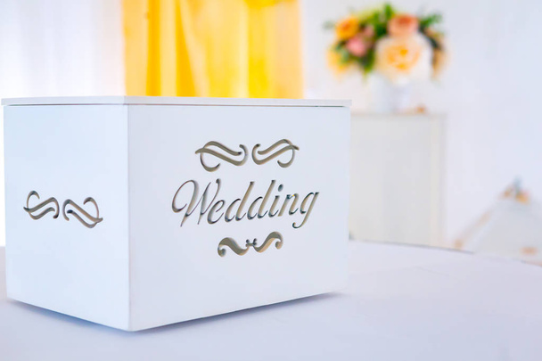 Stylish white wooden box with wedding word. Modern gift box for wedding ceremony. Luxury wedding arrangements and decor. Empty box for greeting cards and presents - Foto, Imagen