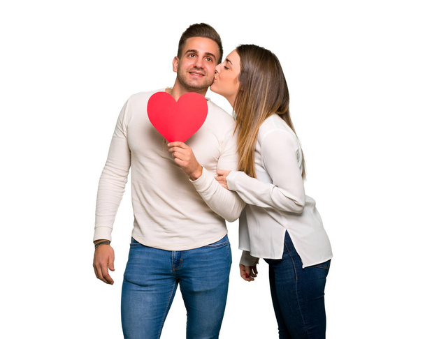 Pareja en día de San Valentín sosteniendo un símbolo del corazón y besándose
 - Foto, Imagen